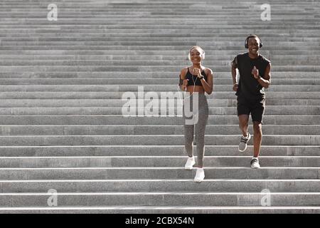 Active Lifestyle. Black Jogger Couple Running Down On Urban Stairs, Training Outdoors Stock Photo