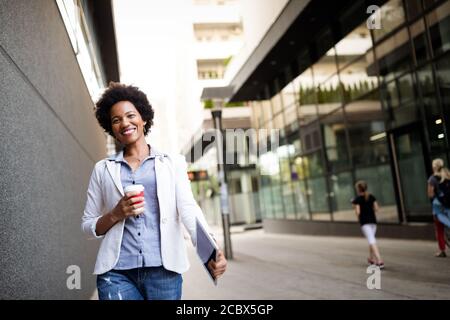 Portrait of smiling african woman walking in the city with tablet