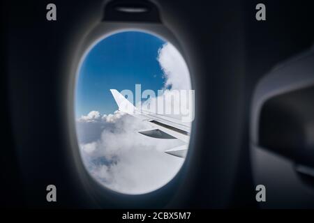 View from airplane window. Wing during flight above clouds at sunny day. Stock Photo
