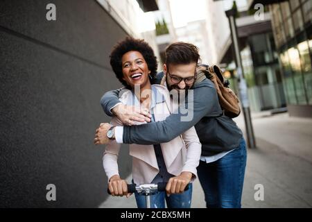 Young couple on vacation having fun driving electric scooter in the city. Stock Photo