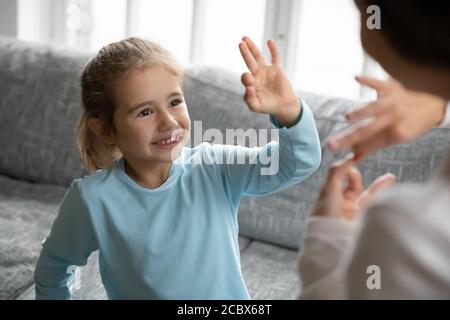 Happy little girl with hearing impairment enjoying communicating with mother. Stock Photo