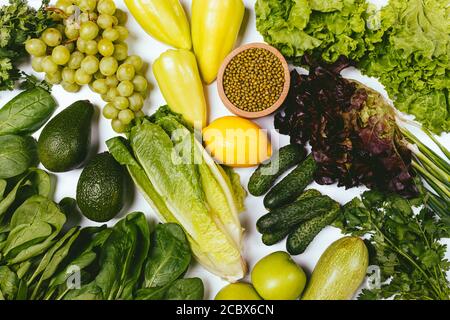 Organic green vegetables, herbs, fruits and mung beans on white background, flat lay clean eating. Stock Photo
