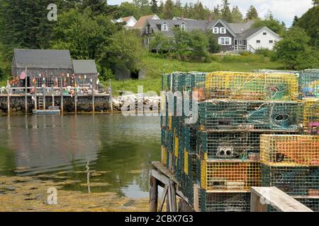 Picturesque fishing village of Port Clyde, Maine. Lobster traps stacked on dock in harbor and lobster shack decorated with colorful buoys. Stock Photo