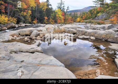 Scenic view of colorful autumn foliage with rocks and clouds reflecting on surface of pool along Swift River in the White Mountains National Forest. Stock Photo
