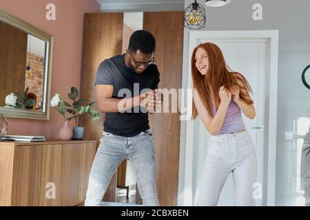 cheerful interracial couple have fun at home, they fool around at weekend, enjoy in dance. love, relationships concept Stock Photo