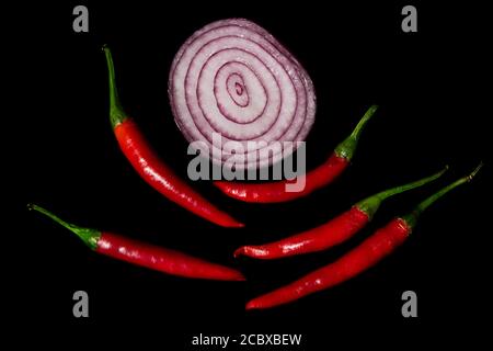 Red small peper and cut striped onion on a black background Stock Photo