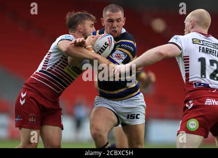 Leeds Rhinos' Cameron Smith (centre) is tackled by Wigan Warriors' Sam Powell (left) and Liam Farrell during the Betfred Super League match at The Totally Wicked Stadium, St Helens. Stock Photo