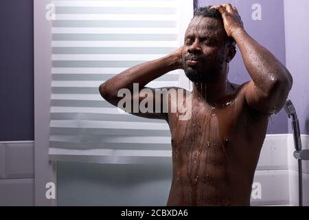 middle aged man in shower cubicle, taking a shower alone. he stands with eyes closed, skincare in the morning Stock Photo