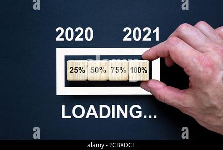 Loading new year 2021 with hand putting wood cube in progress bar. Business concept. Stock Photo