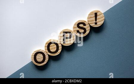 Wood circles with word 'oops' on paper white and blue background, copy space. Business concept. Stock Photo