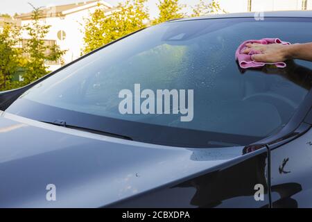 Close up view of male hand cleaning windshield. Vehicle concept background. Stock Photo