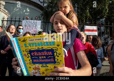 Moscow, Russia. 16th of August, 2020 Dad reads a poem Tarakanishche ('The Monster Cockroach') of popular children's Russian poet Korney Chukovsky at a protest rally against the results of the Belarusian presidential election in front of Belarusian Embassy in Moscow, Russia Stock Photo
