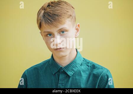 serious young man in a blue shirt on a yellow background Stock Photo