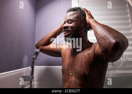 athletic african sportsman take shower after sport workout, fitness. wash away sweat and tiredness under the running water Stock Photo