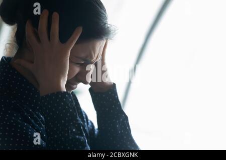 Stressed young indian ethnicity businesswoman suffering from head ache. Stock Photo