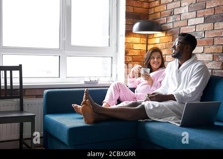 happy multi-ethnic family have rest, talk at home, free time. husband and pregnant wife in modern room interior. the concept of pregnancy, rest and ex Stock Photo