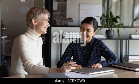 Overjoyed two mixed race female colleagues having fun at meeting. Stock Photo
