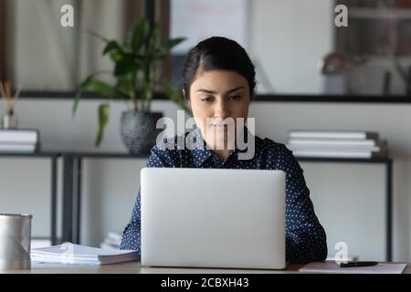 Focused young indian ethnicity businesswoman working on computer in office. Stock Photo
