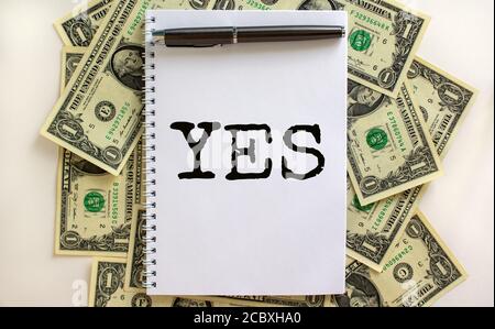 White note with word 'yes' on beautiful background from dollar bills. Metalic pen. Concept. Copy space. Stock Photo
