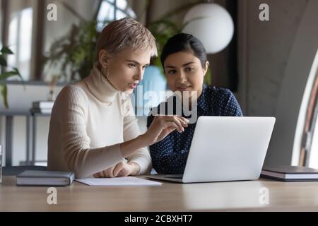 Confident two mixed race businesswomen discussing development strategy. Stock Photo