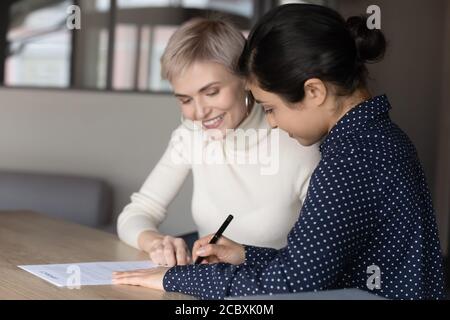 Smiling young professional insurer showing place for signature to client. Stock Photo