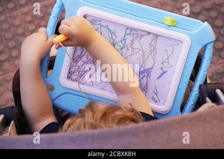 top view of boy sitting in a stroller painting on a blackboard. education concept Stock Photo