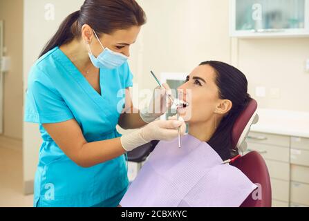 Dentist examining patients teeth and doing checkup in clinic Stock Photo