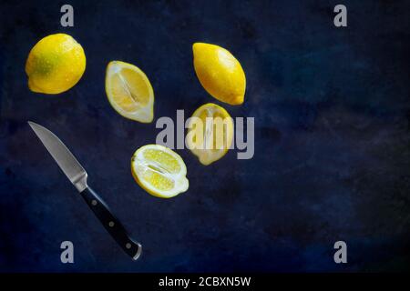 Lemons cuting with fruit Knife in the air on dark background. Food Levitation Stock Photo