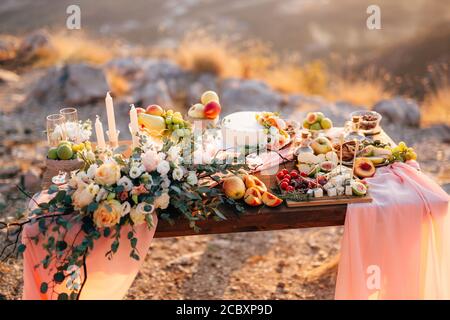 Decorated table for a wedding celebration with a bouquet of white roses, fruits and cake. Stock Photo