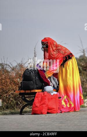 Yugur woman-ethnic attire-terai hat absorbed in luggage reordering. MatiSi complex-Zhangye-Gansu-China-1012 Stock Photo