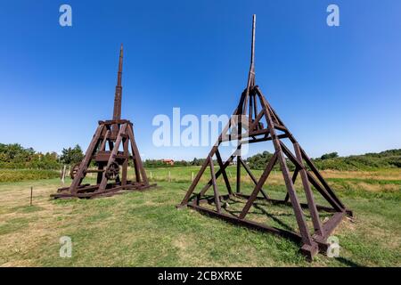 A siege machine standing on the grass in the museum. Medieval wooden machines used for the siege of castles. Summer season. Stock Photo