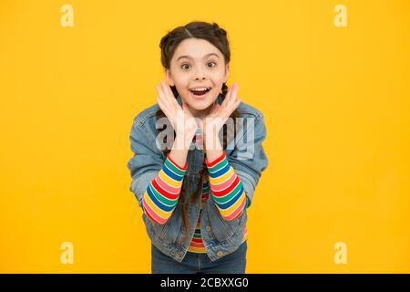 Excited surprised little girl with braids wear denim clothes, childhood dreams concept. Stock Photo