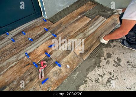 The master precisely glues new floor tiles. The panels look like laminate. Stock Photo
