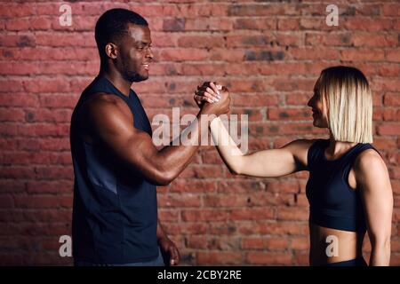 Happy multiethnic diverse athletes congratulating and supporting each other after sports training in a gym. Sport and cooperation concept Stock Photo