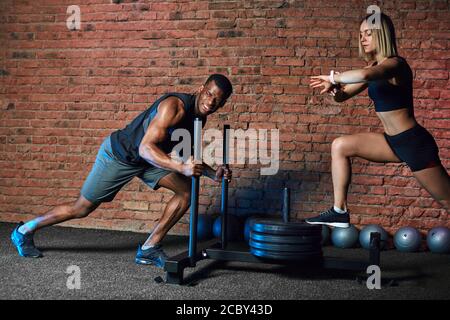 African athlete working out with heavy weight Sled Push machine