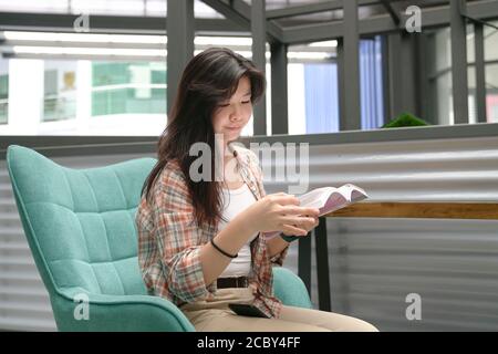 Asian woman sitting on chair and reading a book Stock Photo