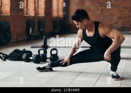 awesome motivated guy doing stretching exercises in the sport center, full length photo. healthcare, wellness Stock Photo