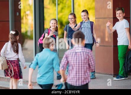 Schoolmates go to school. Students greet each other. Stock Photo