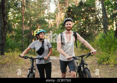 Cycling People. Couple cycle MTB trail track. Outdoor sport activity. Couple With Bikes In Forest. Together on cycle ride in countryside. romantic