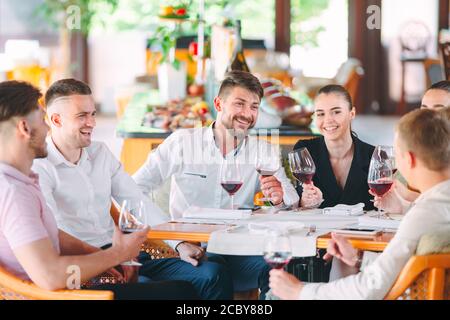 Friends drink wine on the terrace of the restaurant. Stock Photo