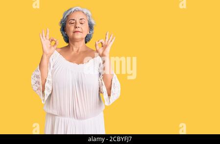 Senior woman with gray hair wearing bohemian style relaxed and smiling with eyes closed doing meditation gesture with fingers. yoga concept. Stock Photo