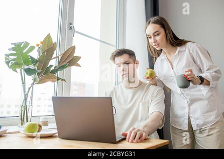 young caucasian guy work from home, he use laptop. man in domestic wear, surf the Net, developing new business project at home. freelance, job,work co Stock Photo