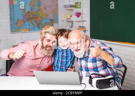 Fathers Day. Happy mature teachers. Senior man using laptop PC with his adult son. Stock Photo
