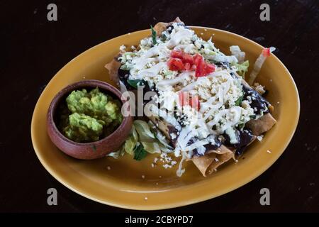 Tacos fritos, or crispy fried Oaxacan tacos stuffed with chicken, covered with queso fresco and served with guacamole on the side.  Oaxaca, Mexico.  A Stock Photo