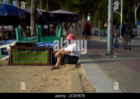 Senior man relaxing at the beach wearing Covid 19 face mask protection of the Coronavirus pandemic. Thailand Southeast Asia Stock Photo