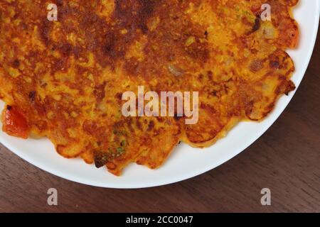 Tomato omelette, is a breakfast pancake prepared mostly in Maharashtra.The main ingredient are gram flour and tomatoes, green chilli, coriander leaves Stock Photo