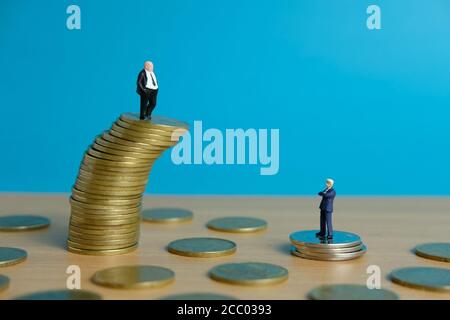 Miniature business concept - business man standing above golden coin stack Stock Photo