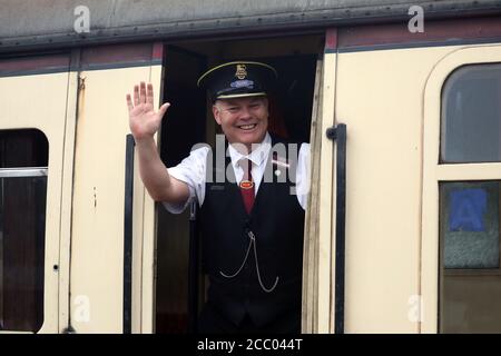 Wansford, UK. 15th Aug, 2020. A Guard waves as the train departs, now that the Nene Valley Railway have resumed running steam trains from Wansford to Peterborough after the COVID-19 Coronavirus pandemic forced them to stop during lockdown. The 92 Squadron Battle of Britain 34081 steam train has been prepared and is ready to go, with the carriages having their capacity reduced to allow for new social distancing guidelines. Credit: Paul Marriott/Alamy Live News Stock Photo