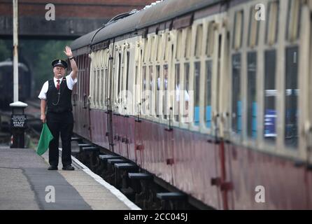 Wansford, UK. 15th Aug, 2020. The guard waves off the the train as the Nene Valley Railway have resumed running steam trains from Wansford to Peterborough after the COVID-19 Coronavirus pandemic forced them to stop during lockdown. The 92 Squadron Battle of Britain 34081 steam train has been prepared and is ready to go, with the carriages having their capacity reduced to allow for new social distancing guidelines. Credit: Paul Marriott/Alamy Live News Stock Photo