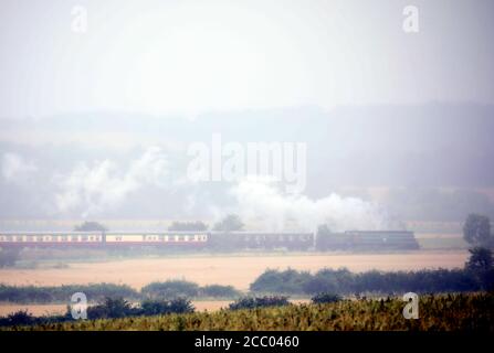 Wansford, UK. 15th Aug, 2020. Heavy rain shrouds the countryside as the Nene Valley Railway have resumed running steam trains from Wansford to Peterborough after the COVID-19 Coronavirus pandemic forced them to stop during lockdown. The 92 Squadron Battle of Britain 34081 steam train has been prepared and is ready to go, with the carriages having their capacity reduced to allow for new social distancing guidelines. Credit: Paul Marriott/Alamy Live News Stock Photo